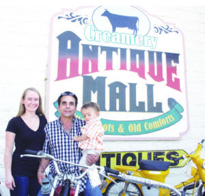 Carrie McEnroe and Brett Mauri and their son Keelan, in front of the sign for their Creamery Antique Mall which is housed in the original Bitterroot Cooperative Creamery building, the construction of which was the impetus for the first Creamery Picnic in 1911. Jean Schurman photo.