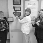 Director of Quality Mira McMasters, Director of Nursing Susan Hill and Business Analyst Pam Chaplin had a lot of fun hanging the new award plaque on the wall at Marcus Daly Memorial Hospital recently. Michael Howell photo.