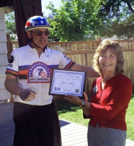 Roger DeBrito of the Bitterroot Trail Preservation Alliance presents Gretchen Spiess of Stevensville with a certificate of appreciation at the Stevensville Hotel Bike Camp on Saturday. “We honored Gretchen not because she rode a bicycle across the country, but because of the kind of person she is,” said DeBrito. Both Spiess and DeBrito rode across the country in the Bikecentennial 40 years ago. Michael Howell photo.